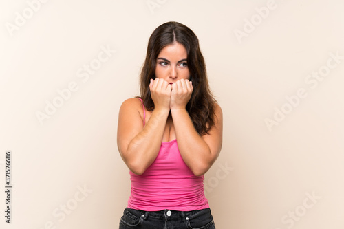 Young woman over isolated white background nervous and scared putting hands to mouth