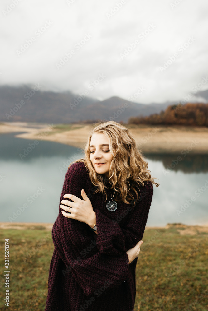 Portrait of beautiful romantic woman standing near lake. She is smiling and enjoying her time. 