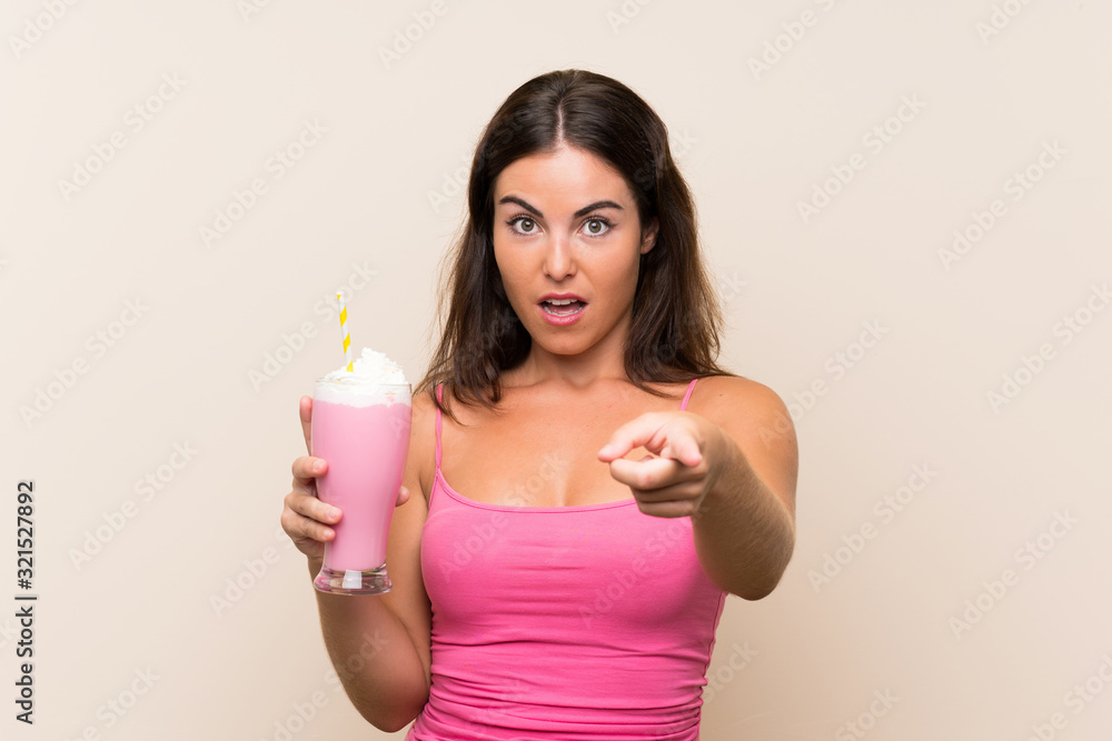 Young woman with strawberry milkshake surprised and pointing front Young woman with strawberry milkshake surprised and pointing front