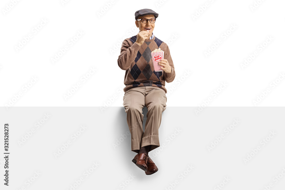 Senior man smiling and sitting on a panel with popcorn Senior man smiling and sitting on a panel with popcorn