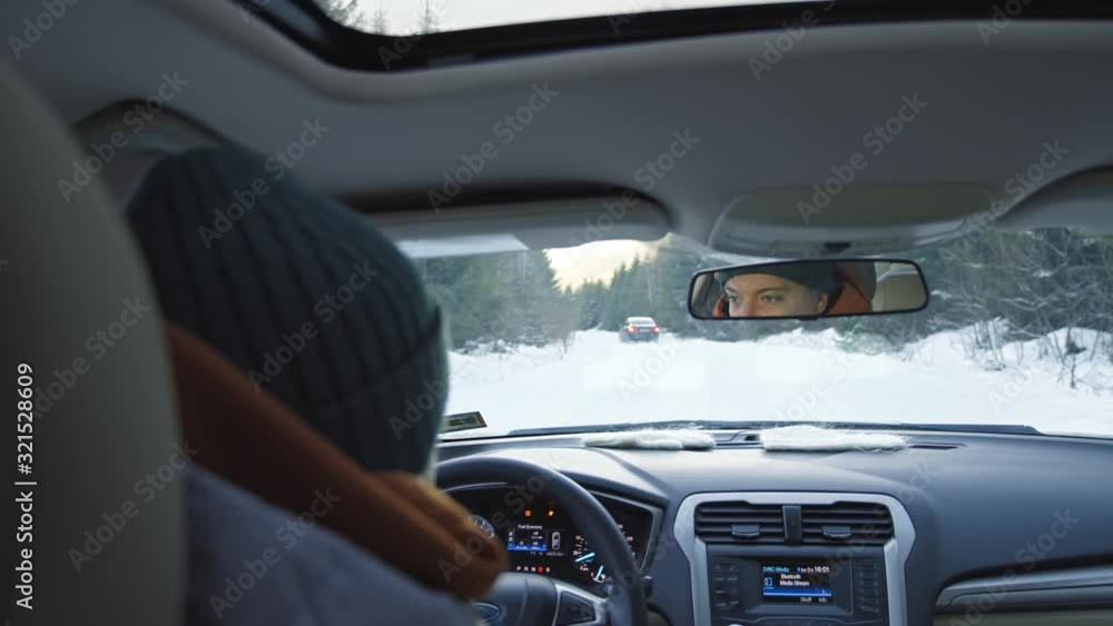 Close-up Caucasian young man driver sitting inside modern car driving on winter snow covered road in mountain forests. Roadtrip. Slow motion. Close-up Caucasian young man driver sitting inside modern car driving on winter snow covered road in mountain forests. Roadtrip. Slow motion.