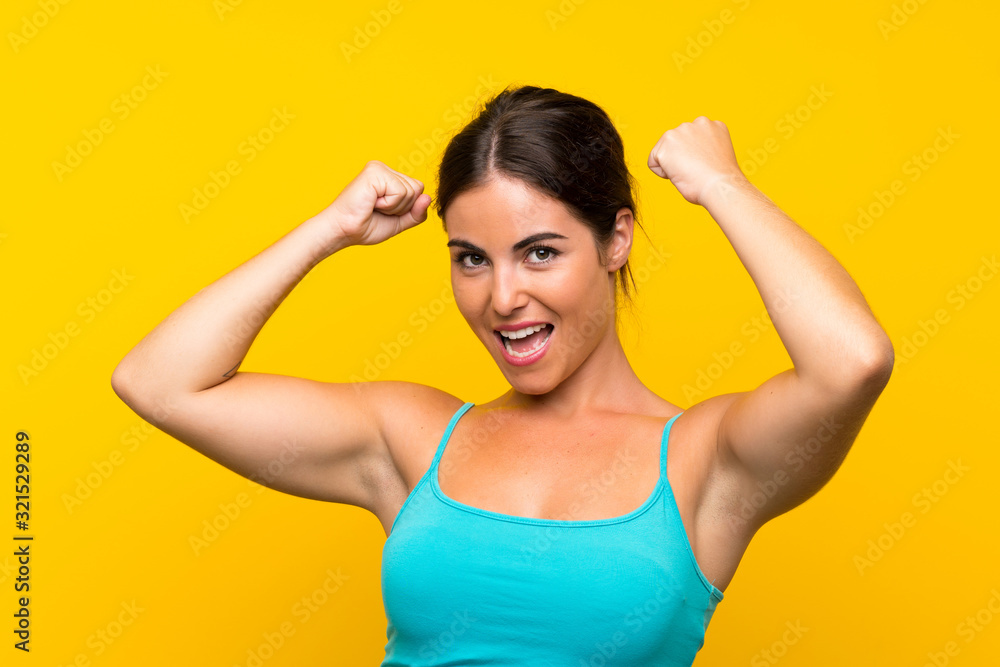 Young woman over isolated yellow background celebrating a victory Young woman over isolated yellow background celebrating a victory