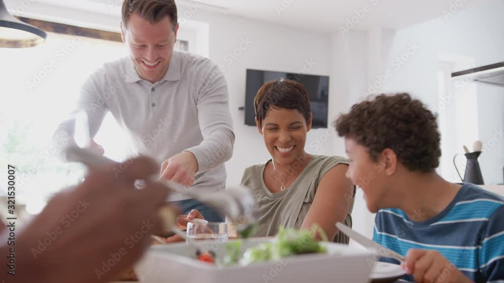 Multi-Generation Mixed Race Family Eating Meal Around Table At Home Together Multi-Generation Mixed Race Family Eating Meal Around Table At Home Together