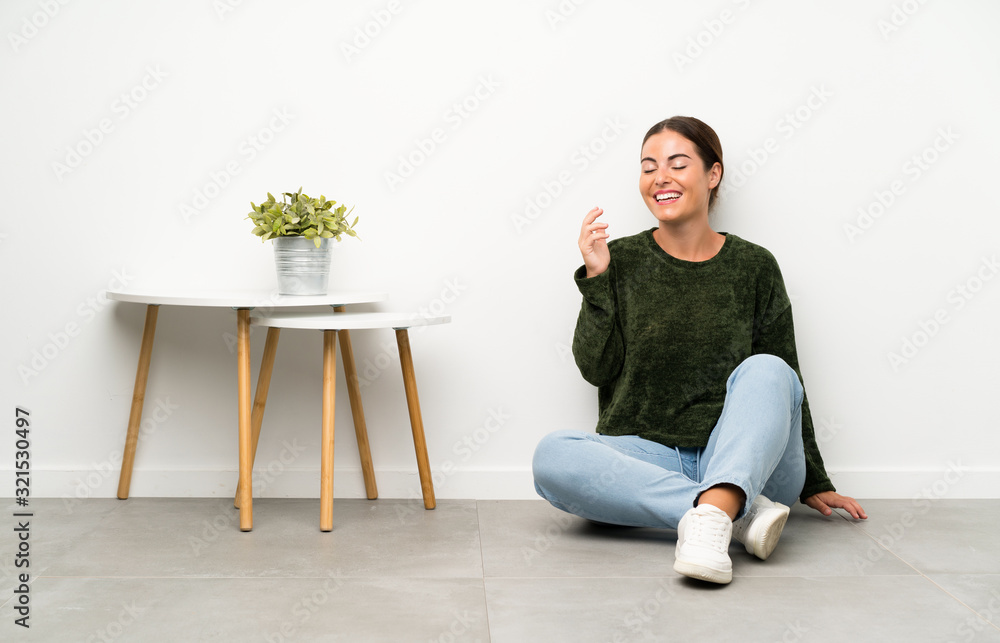 Young woman sitting on the floor laughing