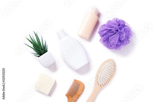 Flat lay photo organic bath products with natural ingredients. Herbal shampoo, hair balm, handmade soap, wooden comb and purple sponge