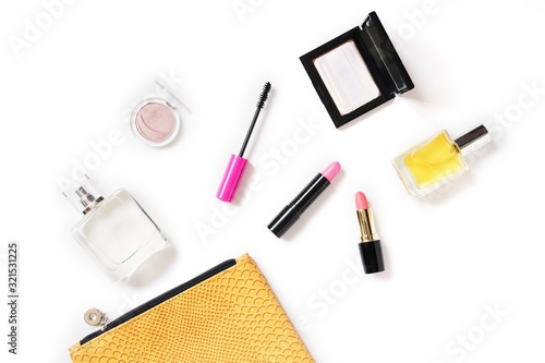 Fototapeta Naklejka Na Ścianę i Meble -  Perfume bottle, compact powder, mascara, pink lipstick and yellow cosmetic bag. Beauty essentials flat lay photo