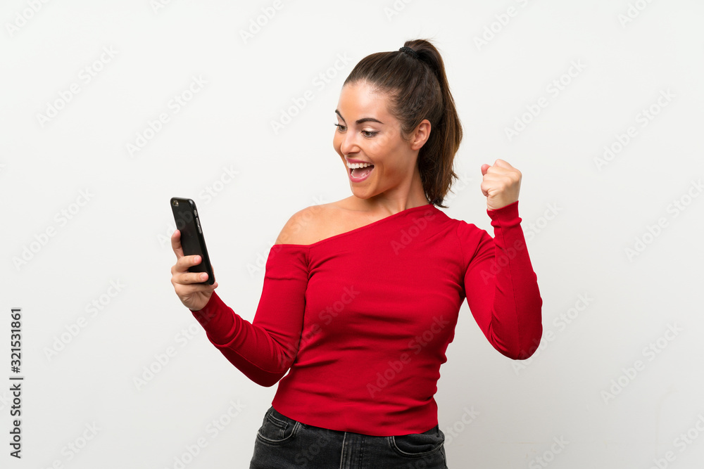 Young woman using mobile phone celebrating a victory Young woman using mobile phone celebrating a victory