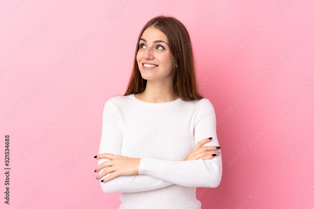 Young woman over isolated pink background looking up while smiling Young woman over isolated pink background looking up while smiling