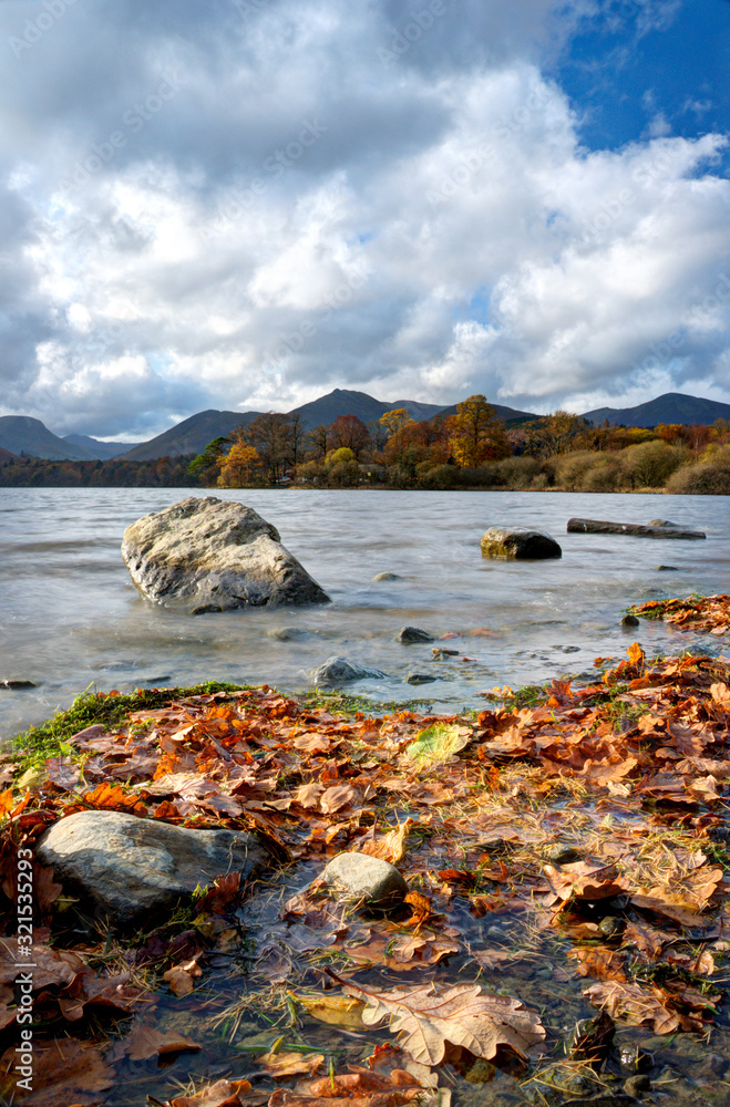 Landscape portrait shot close to the water with colourful leaves during an autumn day in Keswick, Lake District