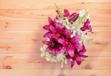 Bouquet of purple lilies and white astilbe and hydrangea flowers on wooden table. Selective focus.