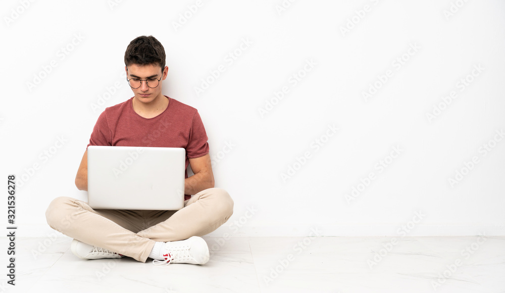 Teenager man sitting on the flor with his laptop Teenager man sitting on the flor with his laptop