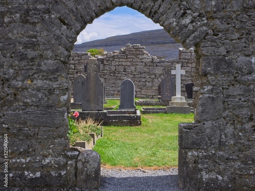 A peak through an archway on the historic cemetry of Corcomroe Abbey   with the hills of the Burren in the background. County Clare,  Ireland