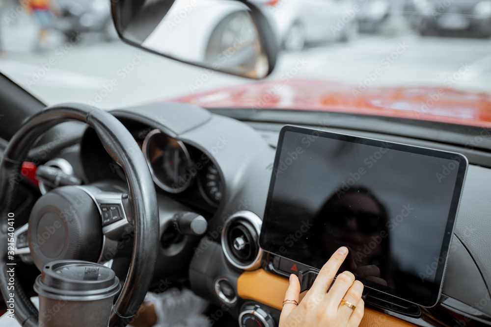 Woman touching digital dashboard while driving electric car, close-up on a touchscreen with black screen. Smart electric car concept