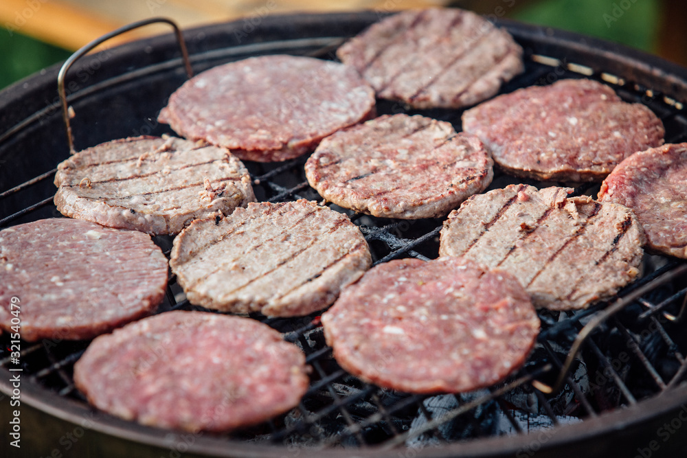 fresh burger cutlets cooked on a grill during an outdoor picnic