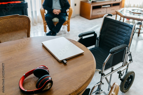 Headphones and laptop with usb-stick on table in living room of senior man photo