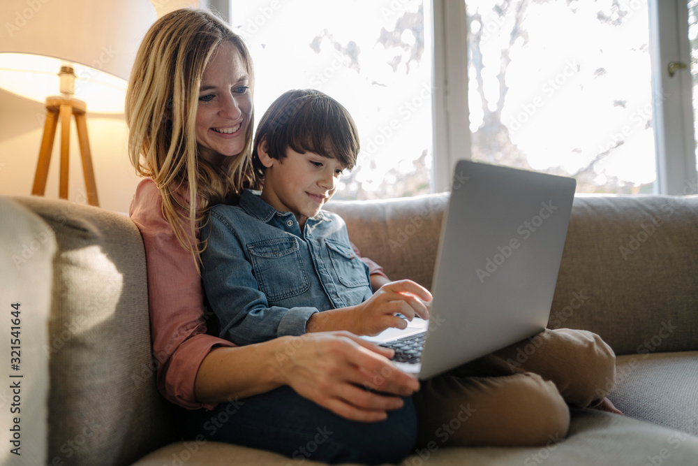 Mother and son sitting on couch, using laptop Mother and son sitting on couch, using laptop