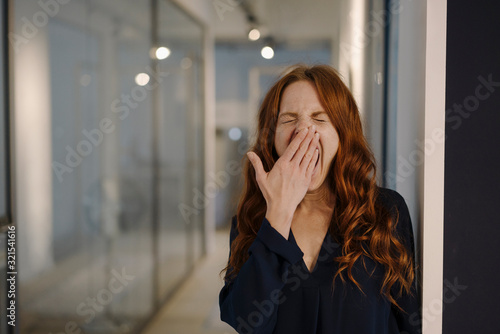 Redheaded woman yawning on office floor