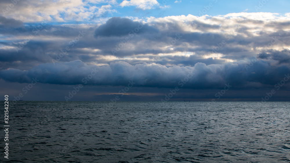 blue dark stormy clouds above the sea and ship on the horizon blue dark stormy clouds above the sea and ship on the horizon