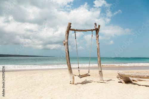 Indonesia, Bali, Jimbaran, Simple wooden swing on sandy coastal beach photo