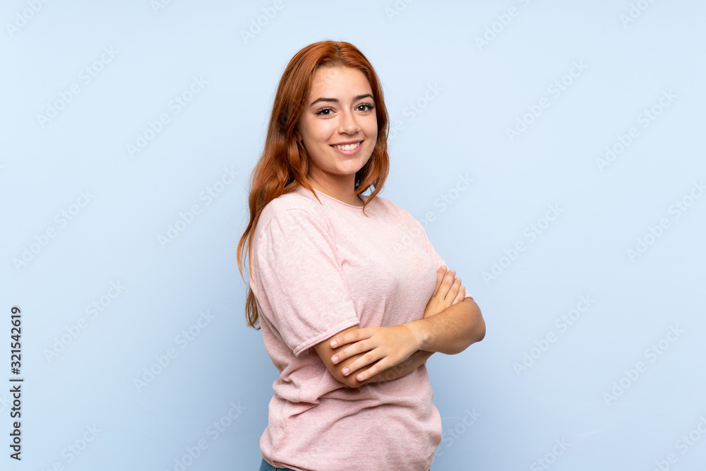 Teenager redhead girl over isolated blue background with arms crossed and looking forward Teenager redhead girl over isolated blue background with arms crossed and looking forward