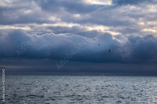 blue dark stormy clouds above the sea and ship on the horizon