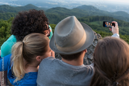Germany, Siebengebirge, back view of four friends taking a selfie with smartphone on Mount Olivet