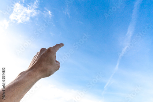 Man's finger pointing up on sky