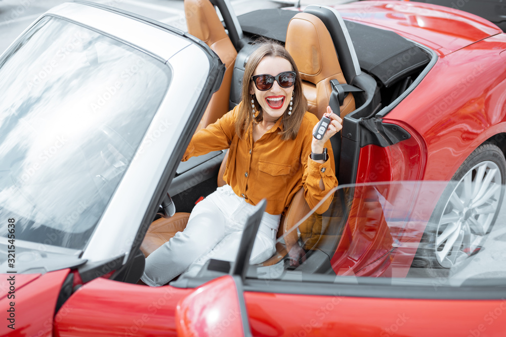 Portrait of cheerful woman feeling happy while sitting in the new sports car. Concept of a happy car buying or renting