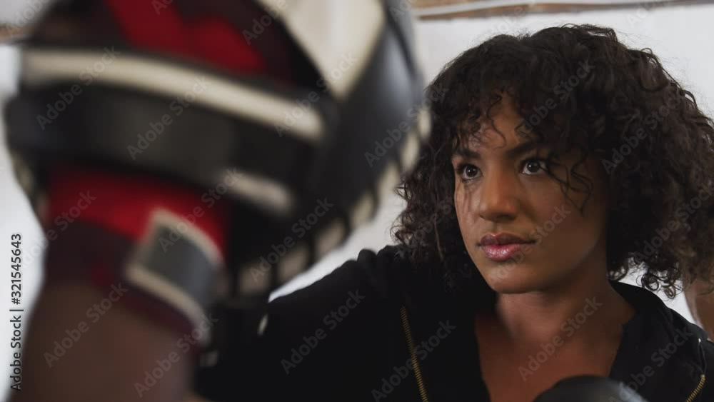 Male Boxing Coach With Female Boxer In Gym Using Training Gloves Male Boxing Coach With Female Boxer In Gym Using Training Gloves