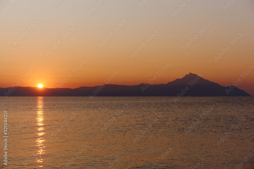 Wonderful sunrise view behind the mountains and next to the sea