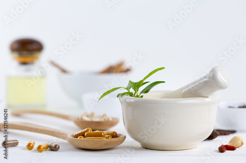 Herbal supplement in capsules on wooden spoon with healthy medicinal plant.Alternative drug or natural pharmaceutical capsule.Medication of vitamin supplemental for care and treatment.