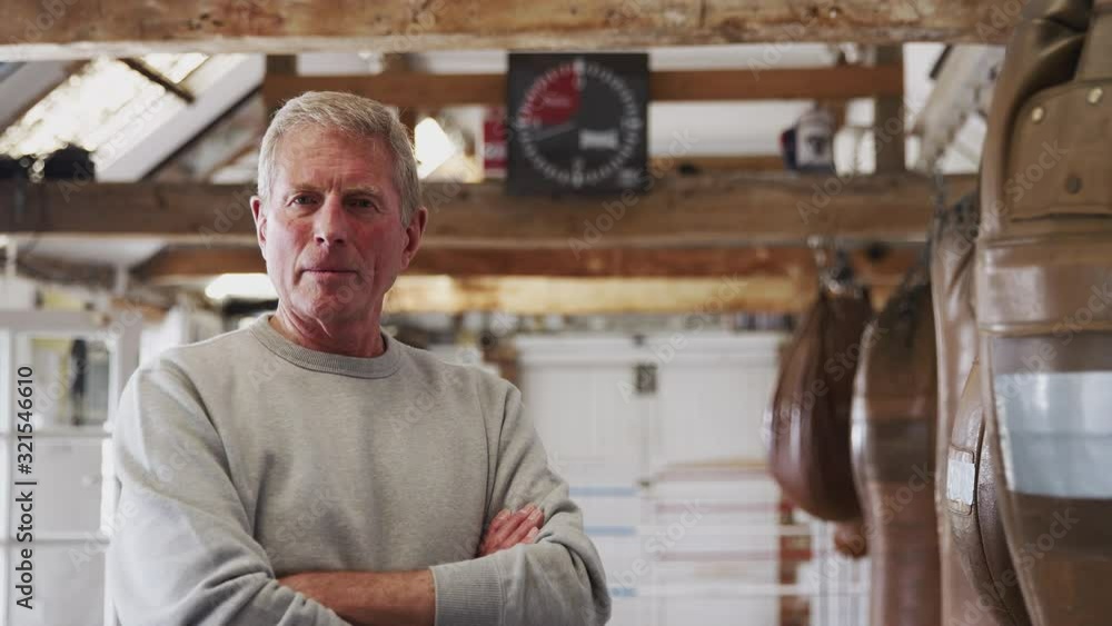 Portrait Of Senior Male Boxing Coach In Gym Standing By Old Fashioned Leather Punching Bags Portrait Of Senior Male Boxing Coach In Gym Standing By Old Fashioned Leather Punching Bags