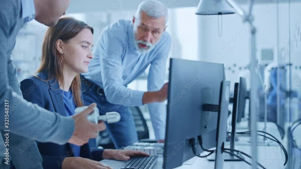 Modern Factory Office: Project Manager and Supervisor Talk to a Female Engineer Works on Computer. Team of Professionals Solving Heavy Industry Problems, Having Discussion, Pointing at Display Modern Factory Office: Project Manager and Supervisor Talk to a Female Engineer Works on Computer. Team of Professionals Solving Heavy Industry Problems, Having Discussion, Pointing at Display