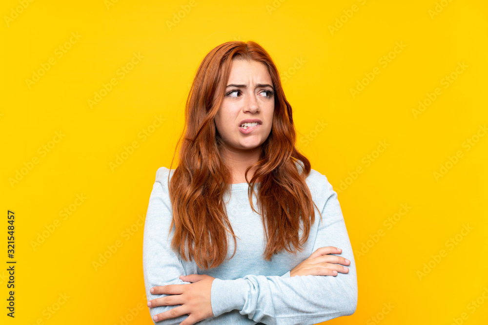 Teenager redhead girl over isolated yellow background with confuse face expression Teenager redhead girl over isolated yellow background with confuse face expression