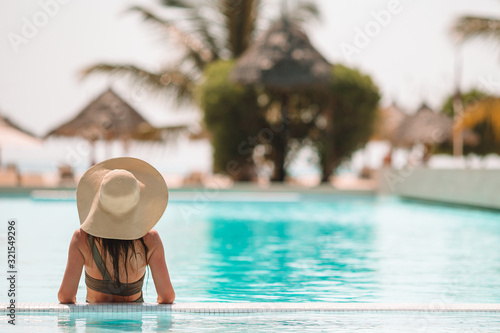 Woman relaxing by the pool in a luxury hotel resort enjoying perfect beach holiday vacation photo