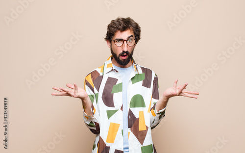 young cool bearded man expressing a concept against flat wall photo