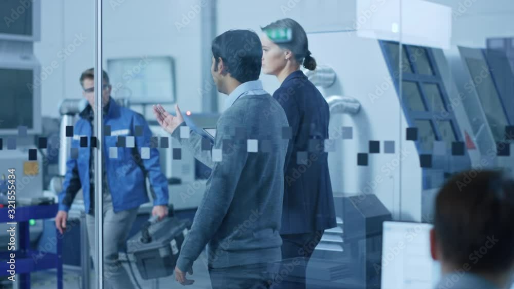 Modern Factory: Female Project Manager and Male Engineer Walk Through High Tech Development Facility, Talking and Using Tablet Computer. High-Tech Facility with CNC Machinery Robot Arm Production Line Modern Factory: Female Project Manager and Male Engineer Walk Through High Tech Development Facility, Talking and Using Tablet Computer. High-Tech Facility with CNC Machinery Robot Arm Production Line