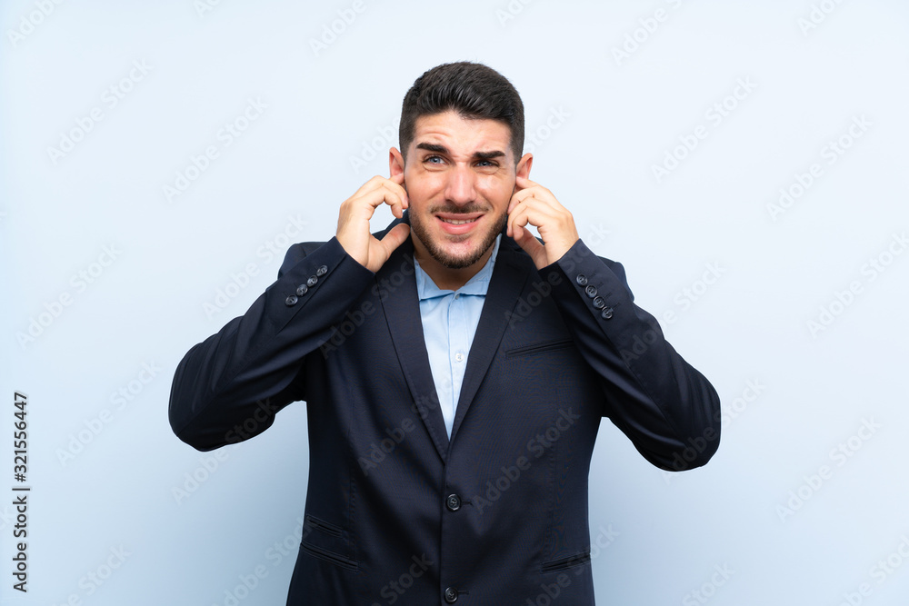 Handsome man over isolated blue background frustrated and covering ears Handsome man over isolated blue background frustrated and covering ears