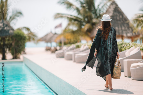 Murais de parede Woman relaxing by the pool in a luxury hotel resort enjoying perfect beach holid