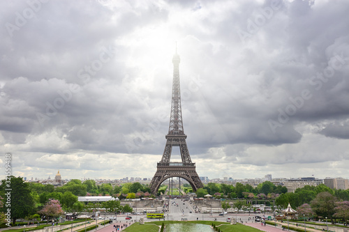 Paris  France. Panoramic image of Eiffel tower with dramatic sky grey clouds with sun beams. Symmetrical balanced picture was taken from the axis of fountains of Trocadero in Spring.
