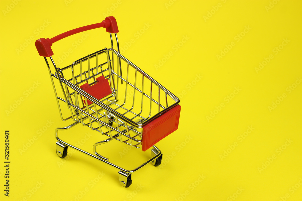 Mini supermarket cart, trolley on a yellow background. Purchases Mini supermarket cart, trolley on a yellow background. Purchases
