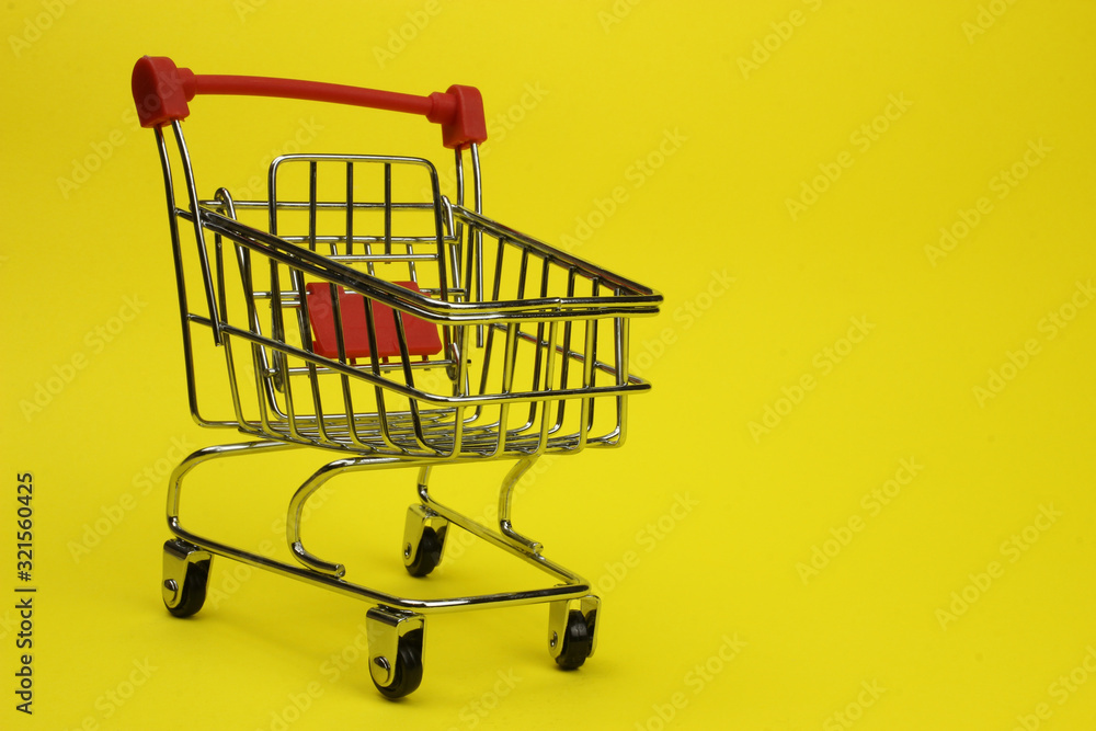 Mini supermarket cart, trolley on a yellow background. Purchases