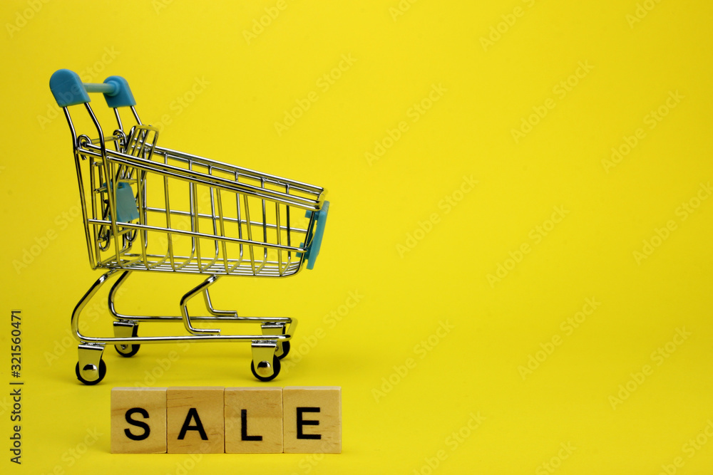 Mini supermarket cart, trolley on a yellow background. Purchases. The Word Sale