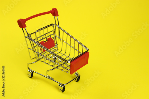 Mini supermarket cart, trolley on a yellow background. Purchases