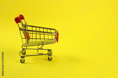 Mini supermarket cart, trolley on a yellow background. Purchases