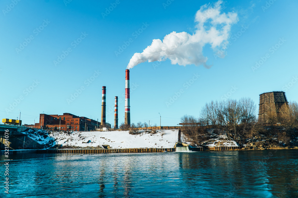Smoking pipes of the plant against the blue sky, white smoke from the pipes Smoking pipes of the plant against the blue sky, white smoke from the pipes