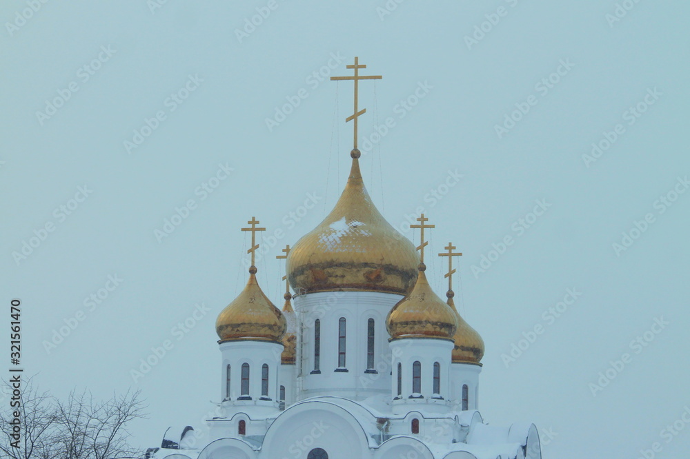 Golden domes and crosses of a white Orthodox Christian church against the sky