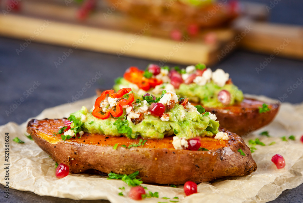 Healthy food - Baked sweet potatoes served with guacamole, feta cheese and pomegranate