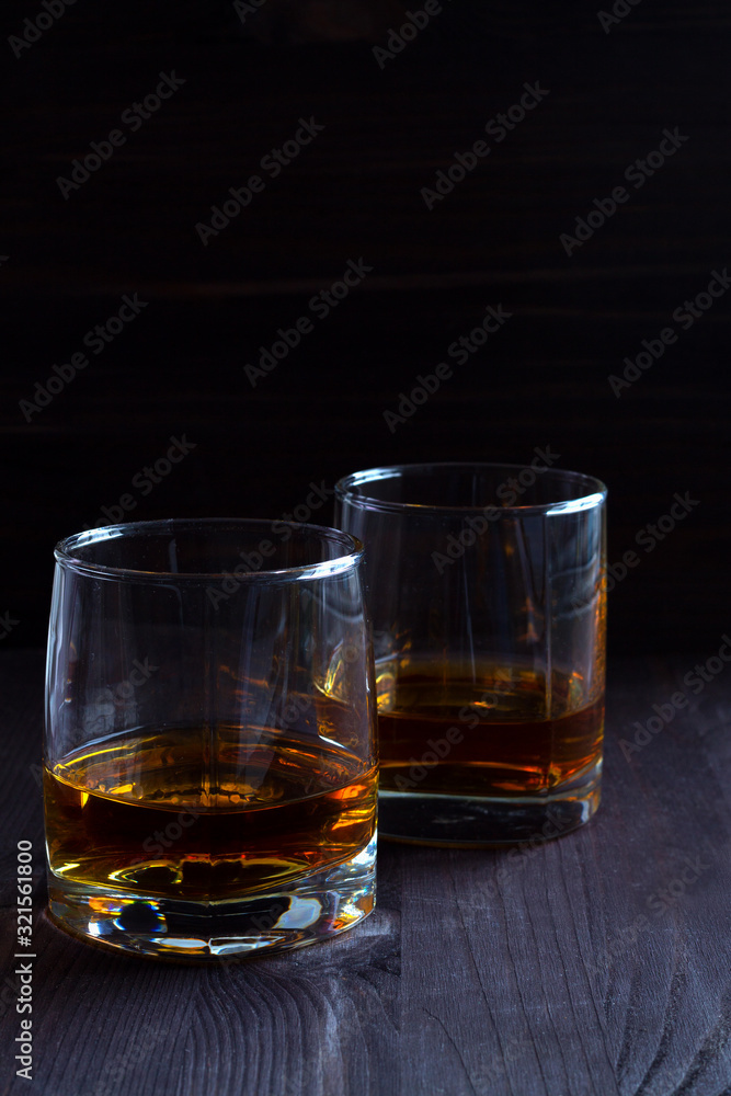 alcoholic drinks. glass of whiskey on a black background. two glasses of whiskey on a wooden background. horizontal orientation alcoholic drinks. glass of whiskey on a black background. two glasses of whiskey on a wooden background. horizontal orientation