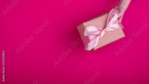 A beautiful gift box with satin ribbon in hand.